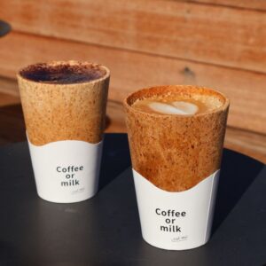 Two edible coffee cups filled with hot coffee beverages on a café table, offering a sustainable zero-waste alternative to disposable cups
