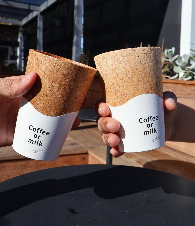 Two people toasting with edible coffee cups, promoting a sustainable and zero-waste coffee experience.